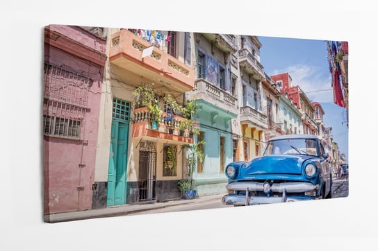 Obraz na płótnie HOMEPRINT, niebieski zabytkowy klasyczny amerykański samochód, kolorowa uliczka, Hawana, Kuba 100x50 cm HOMEPRINT