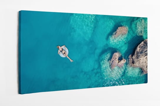 Obraz na płótnie HOMEPRINT,  widok z góry na kobietę pływającą w pontonie na oceanie 100x50 cm HOMEPRINT